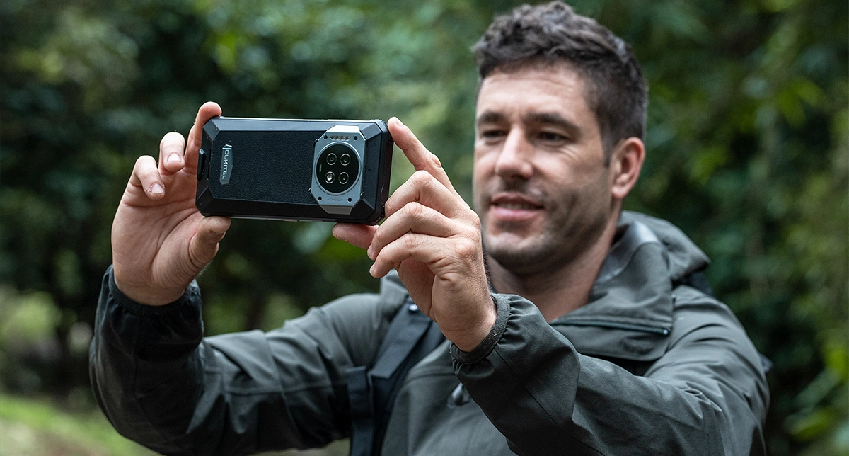 یک شخص درحال عکاسی در جنگل با گوشی‌های مناسب سفر Oukitel